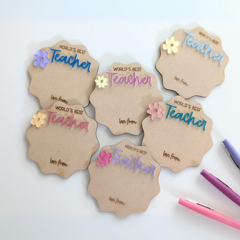A set of custom acrylic magnets with the message "World's Best Teacher," each in different colors and decorated with flower accents. These magnets can be personalized as unique teacher gifts.