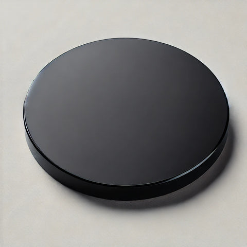 A smooth black acrylic disc with a sleek, glossy surface that highlights the deep, rich color for sampling and design purposes.