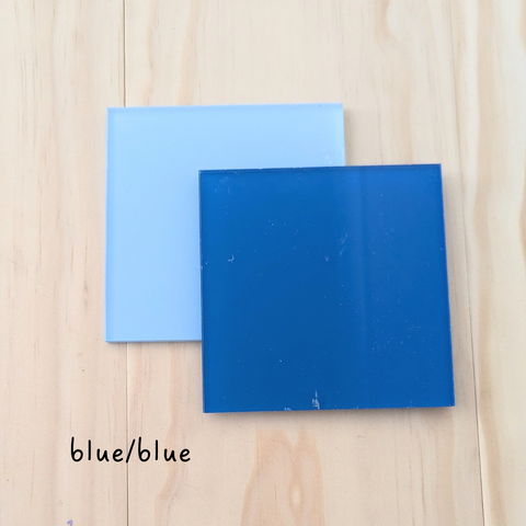 Two square acrylic color samples in light blue and dark blue, displayed on a wooden background with the label "blue/blue.